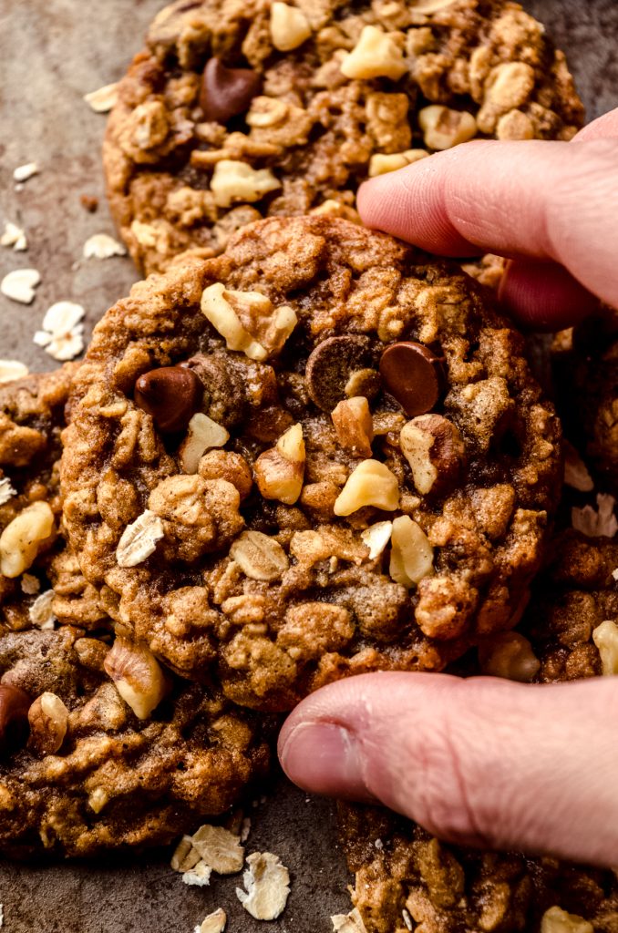 A photo of someone holding an oatmeal walnut chocolate chip cookie/