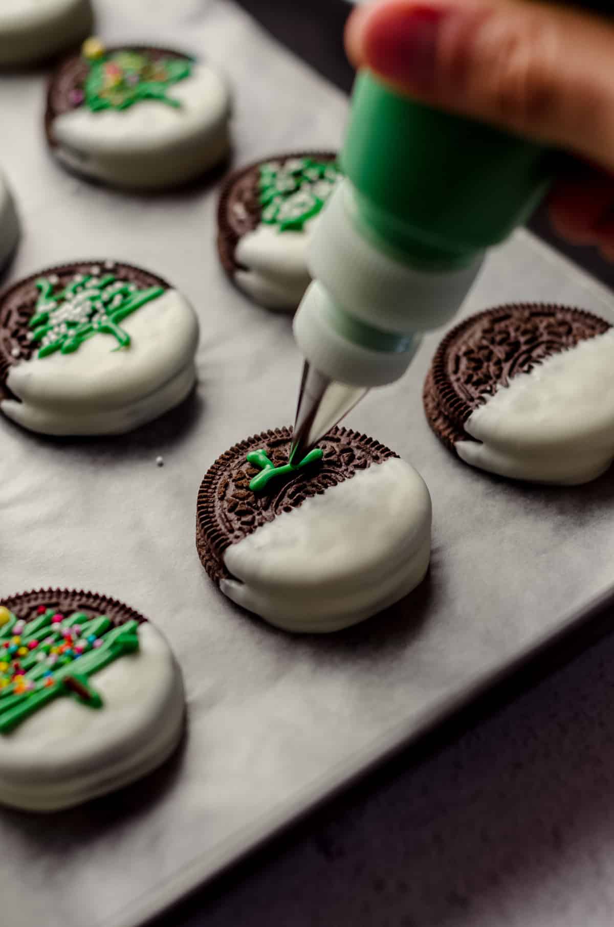 piping christmas trees onto oreos dipped in chocolate