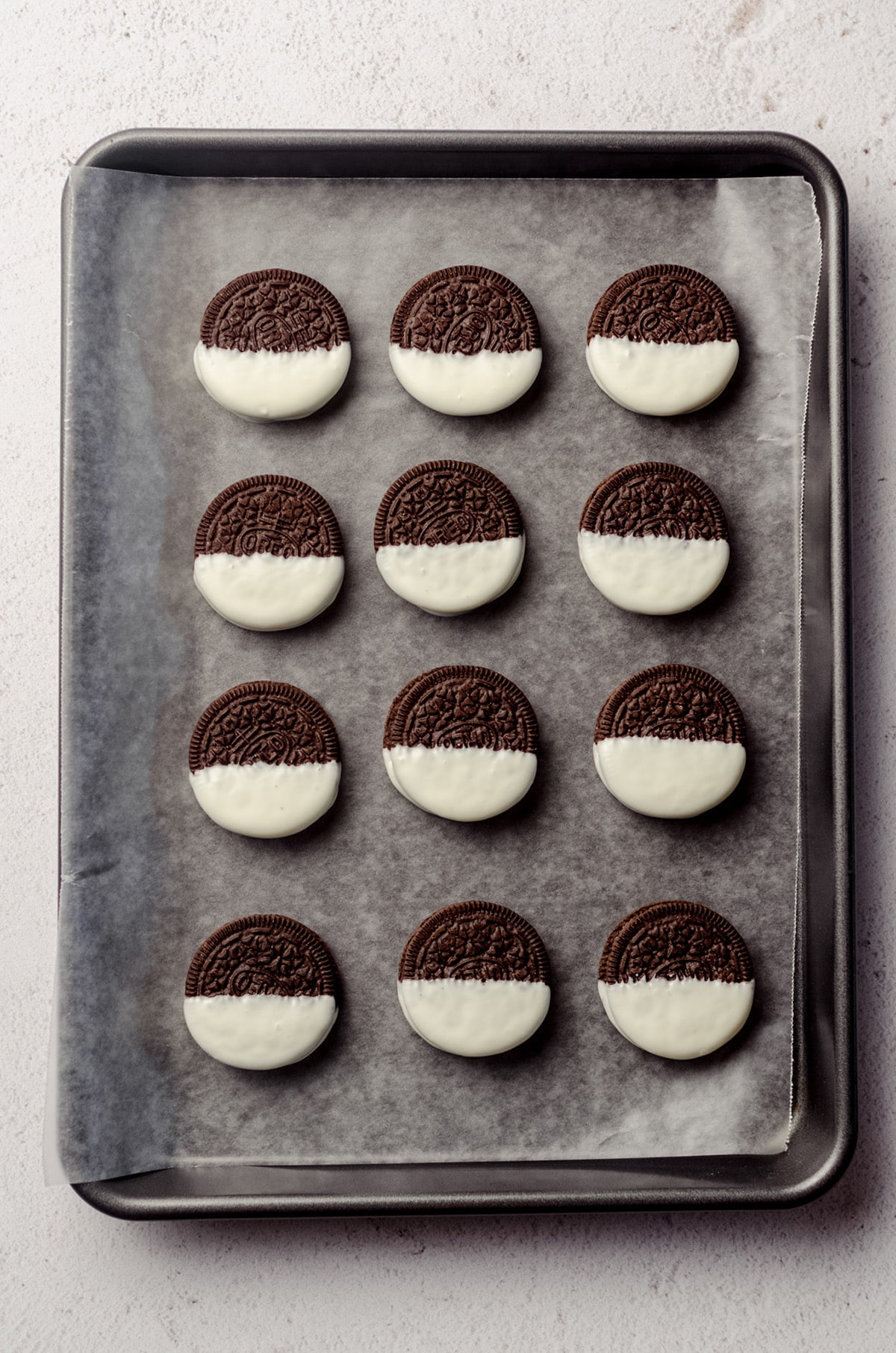 white chocolate dipped oreos on a baking sheet