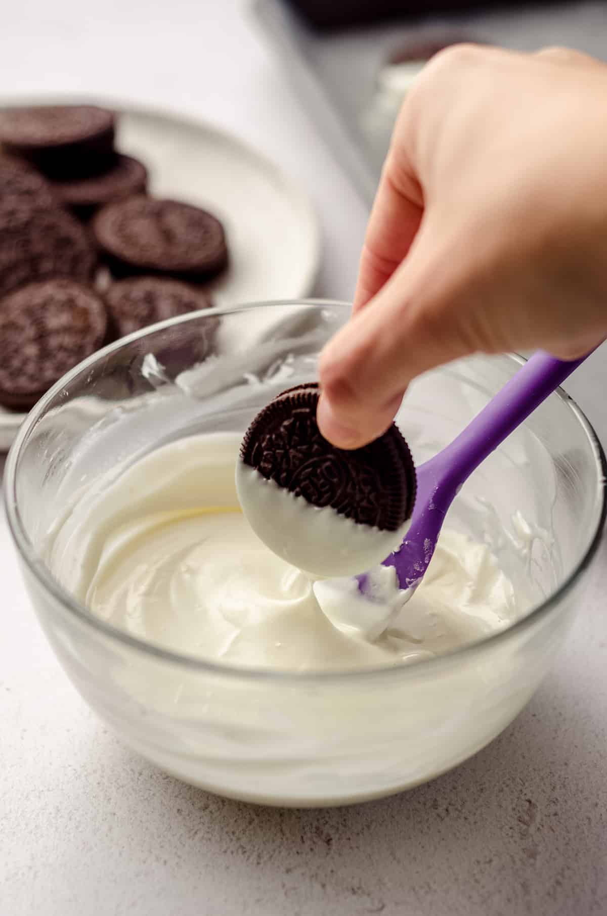 hand dipping oreo into white chocolate