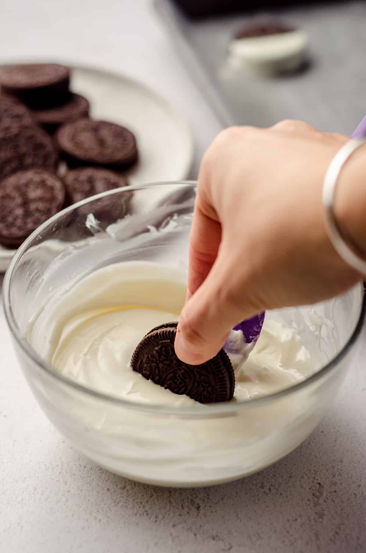 hand dipping oreo into white chocolate