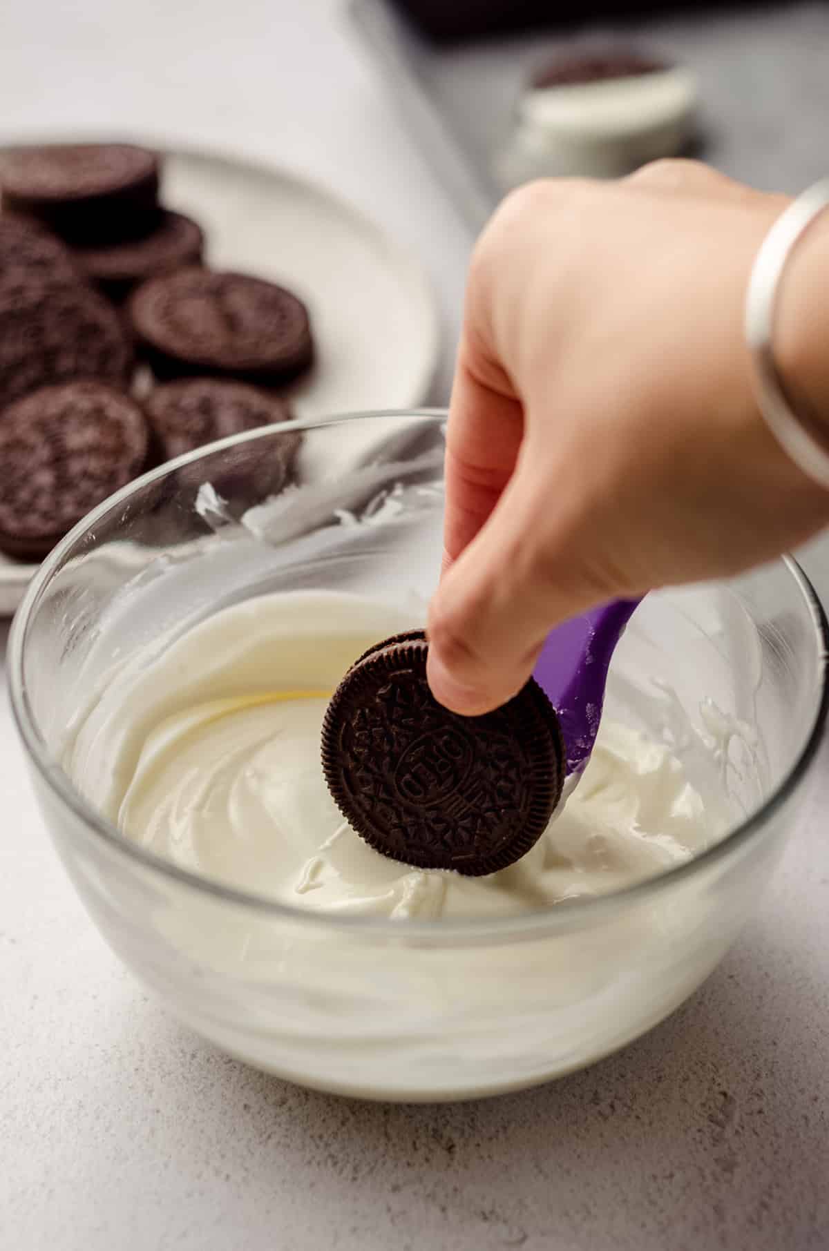 hand dipping oreo into white chocolate