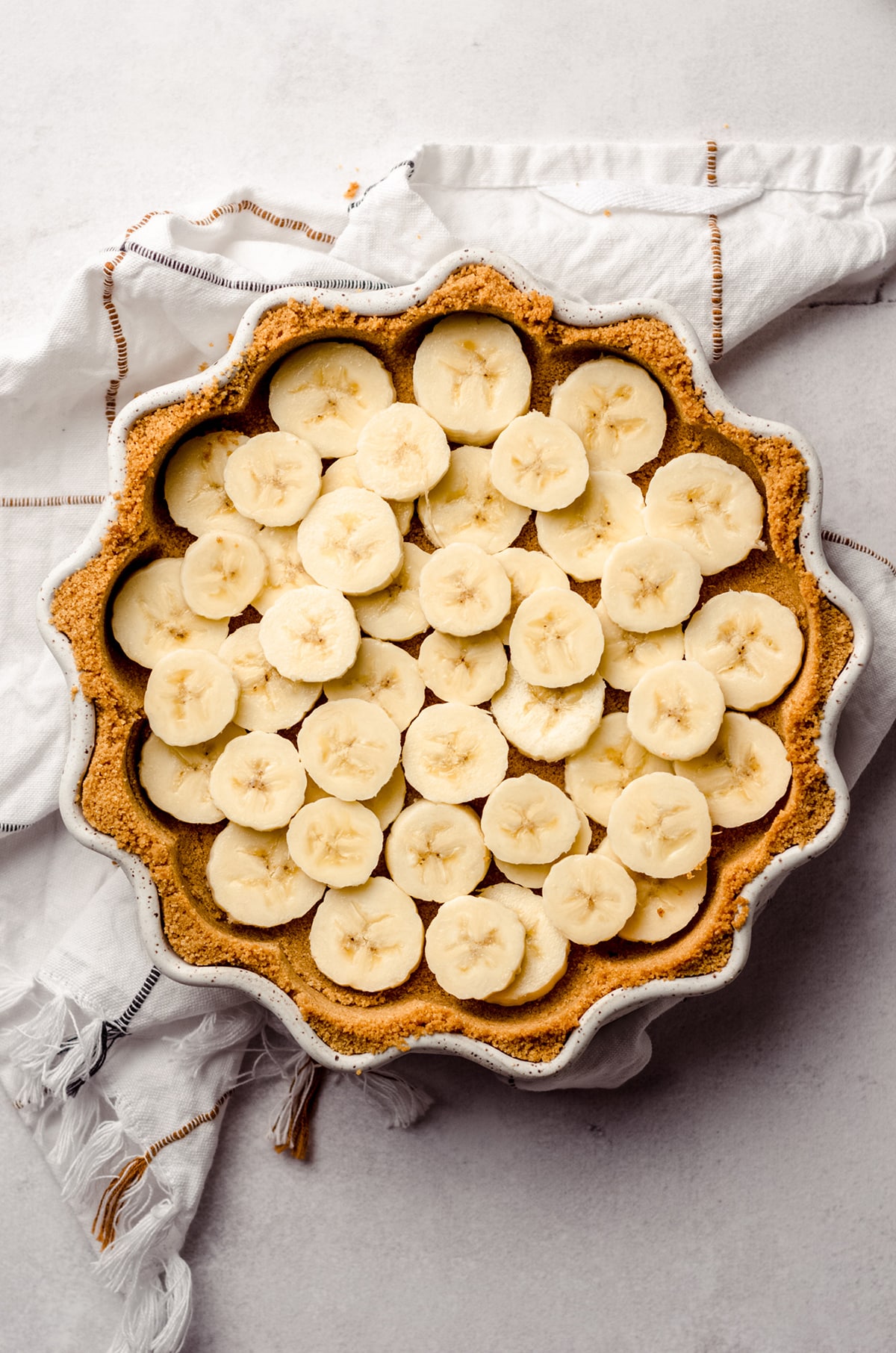 aerial photo of banana layer in a graham cracker crust for banoffee pie