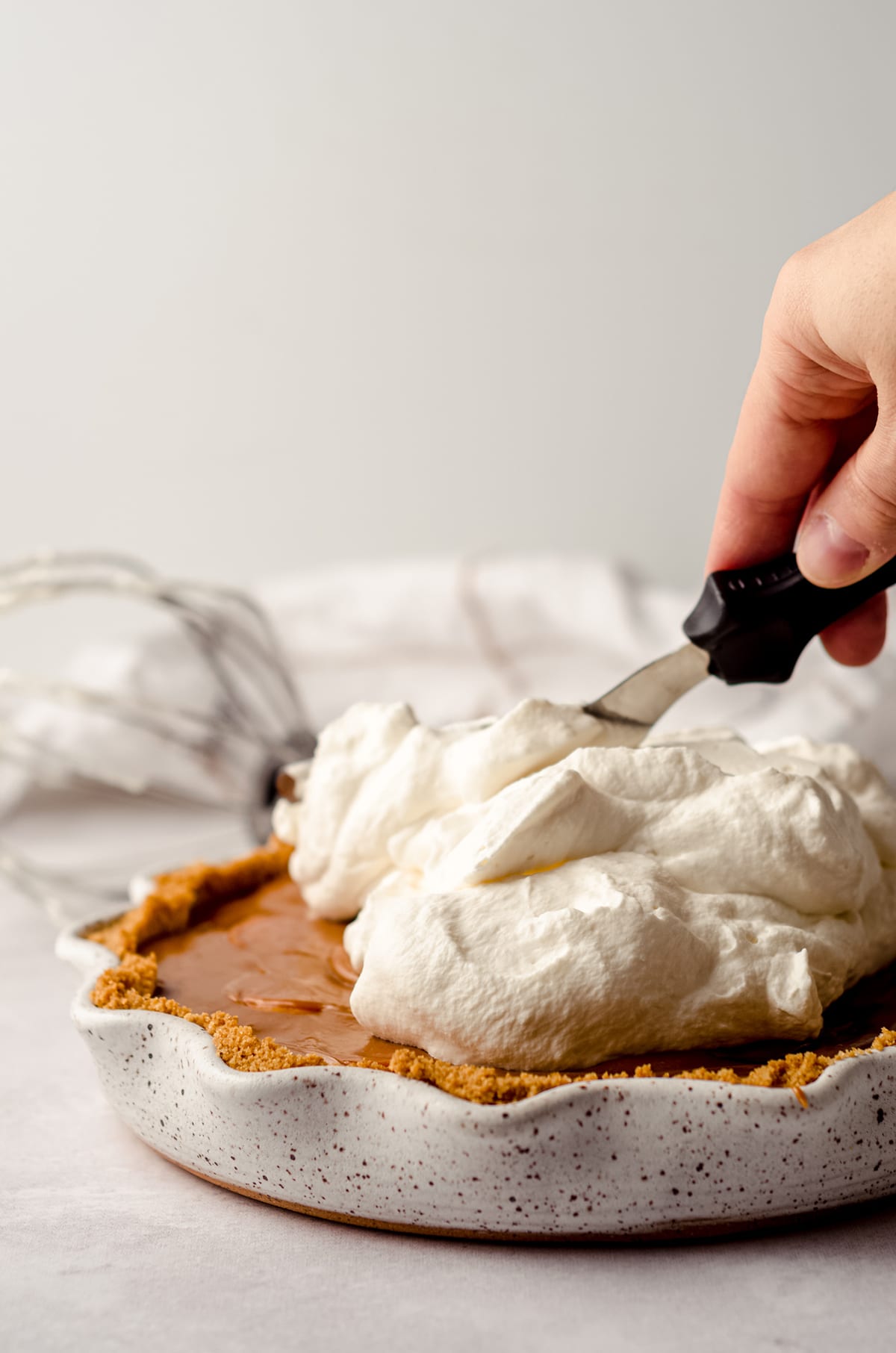 spreading whipped cream onto banoffee pie