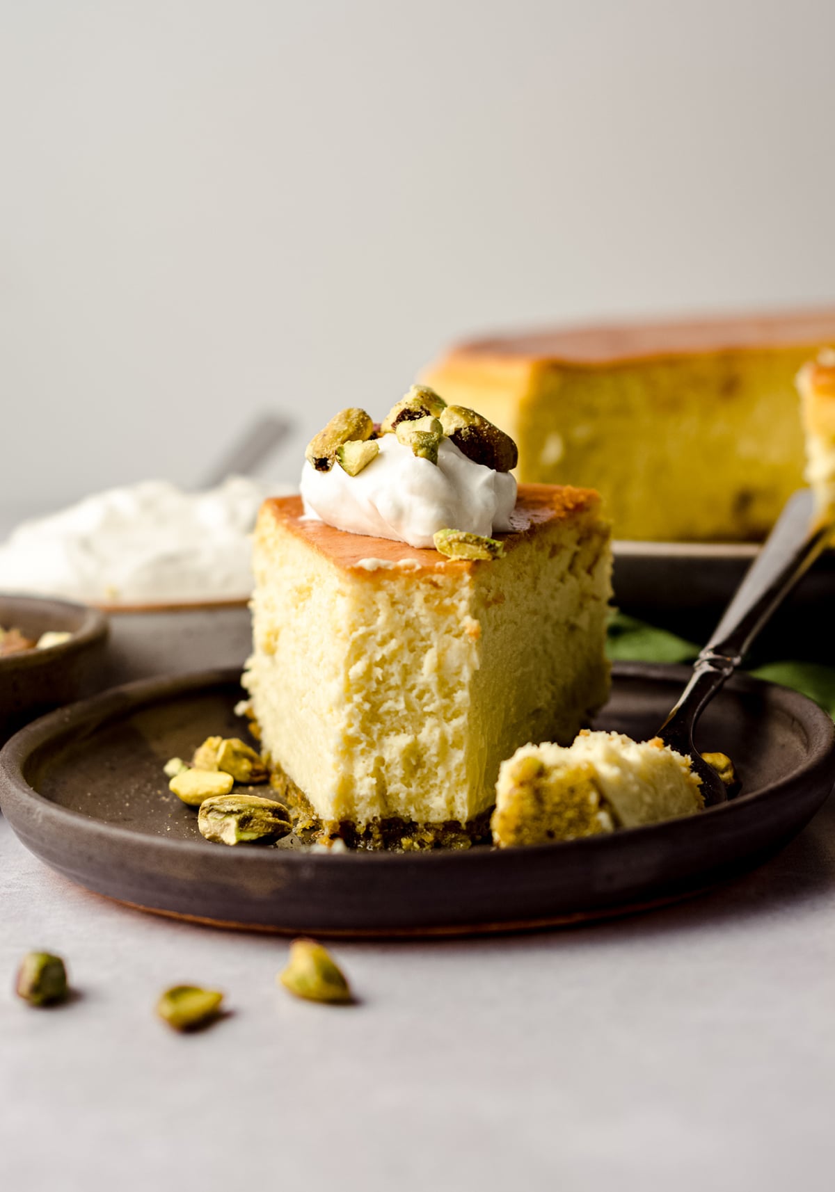 slice of pistachio cheesecake on a plate with a bite taken out of it