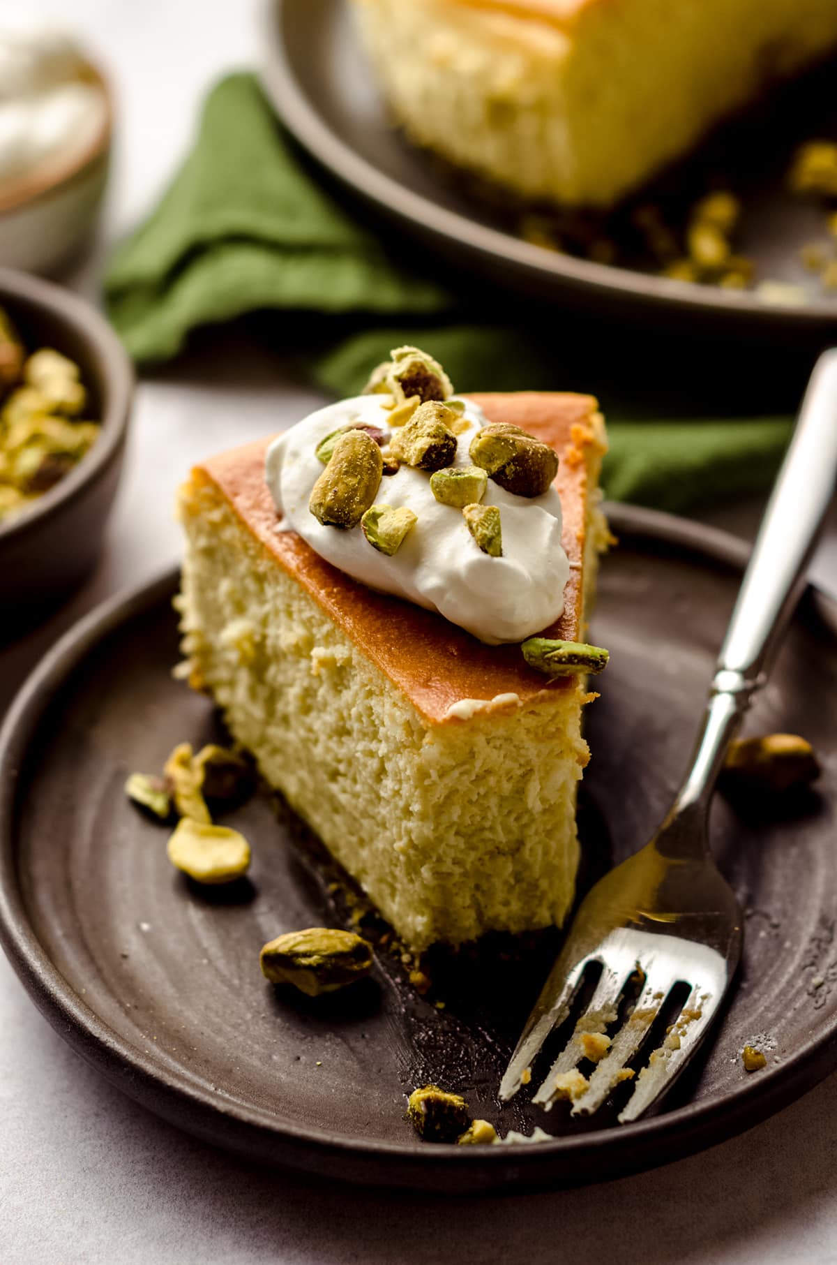 slice of pistachio cheesecake on a plate with a bite taken out of it