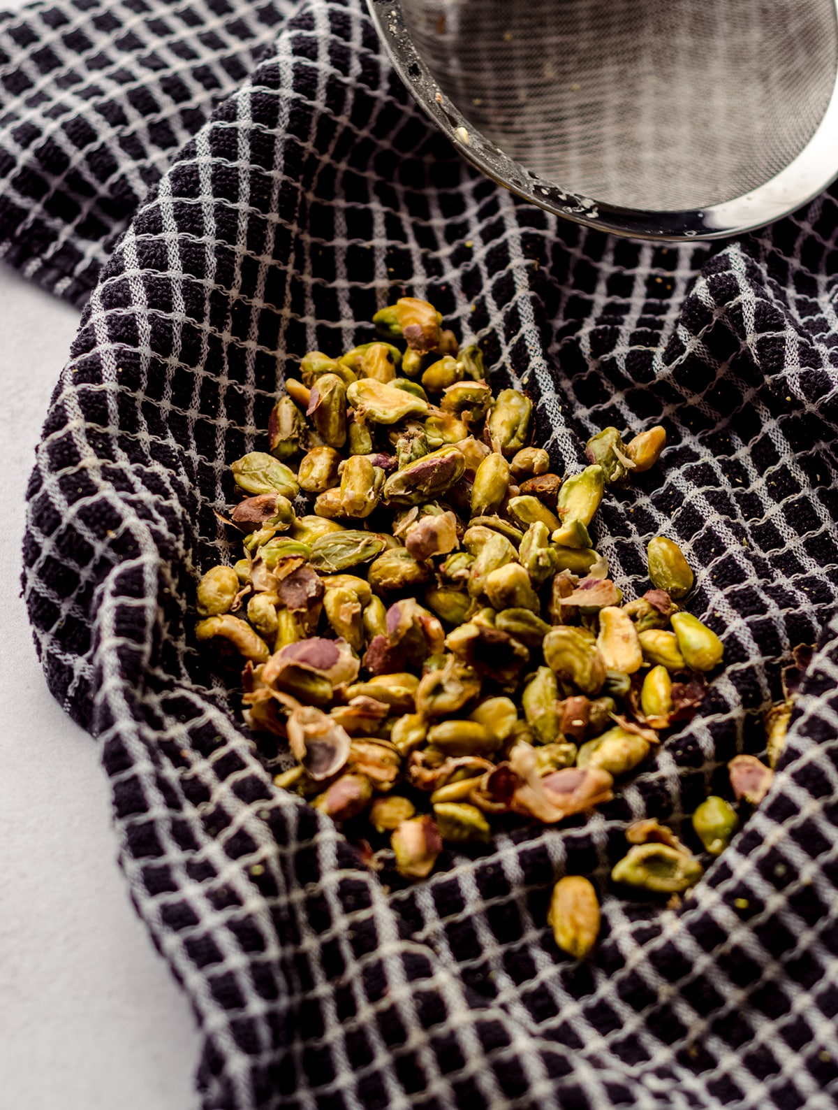 blanched pistachios in a kitchen towel to remove skins