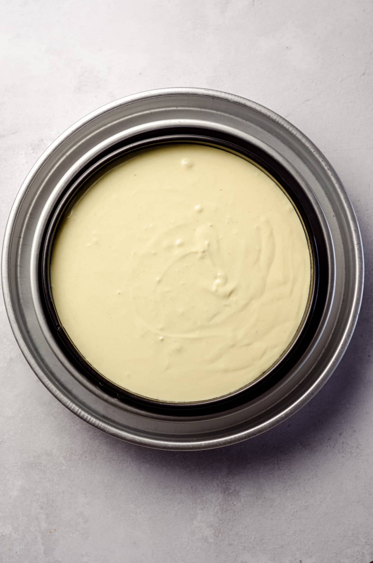 aerial photo of pistachio cheesecake batter in a pan in a water bath ready to bake