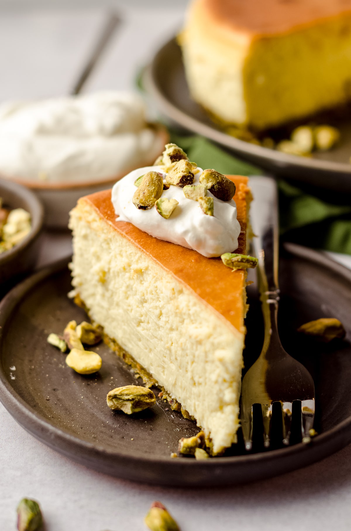 slice of pistachio cheesecake with a dollop of homemade whipped cream on top