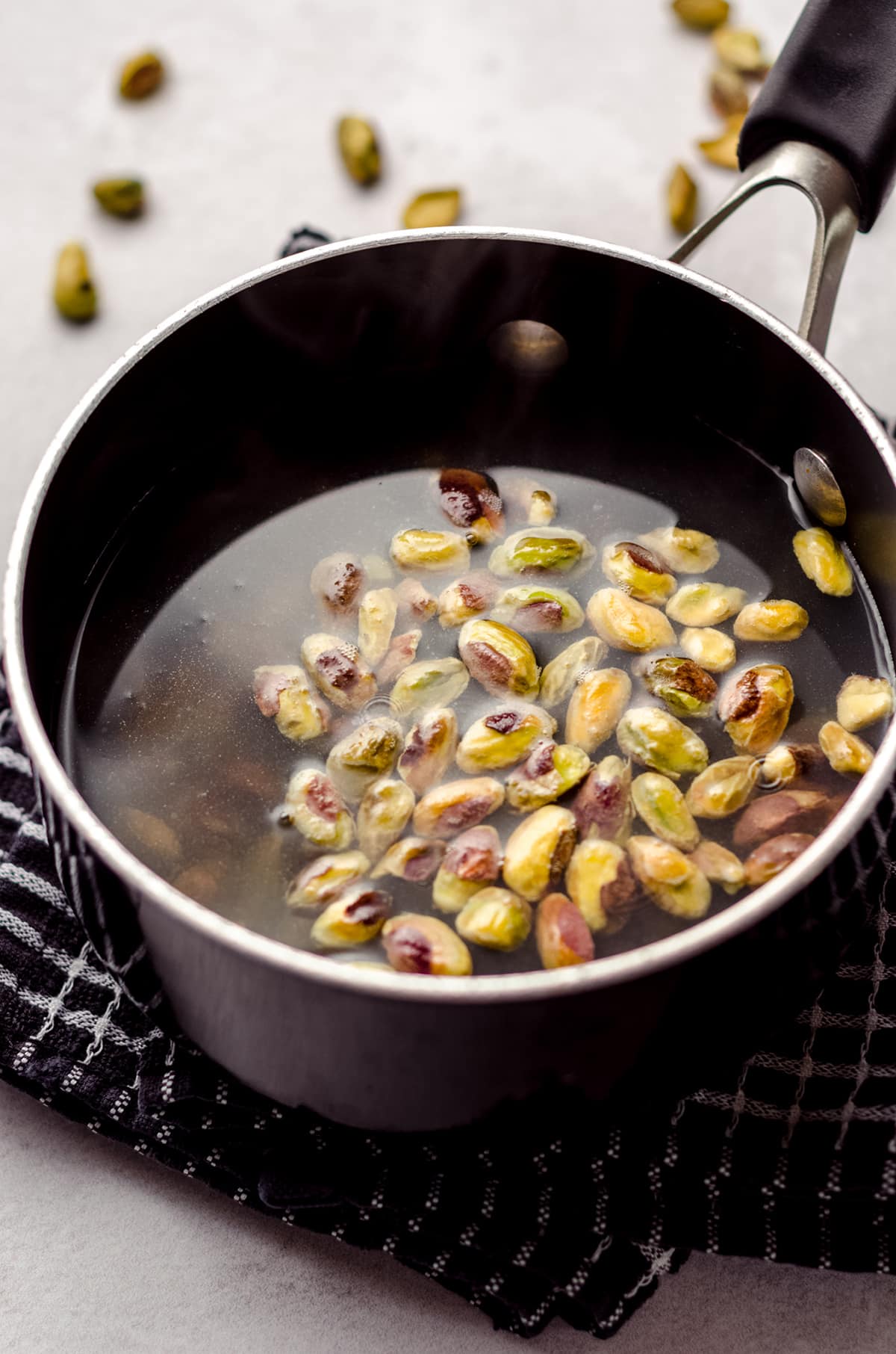 blanching pistachios in a saucepan of hot water
