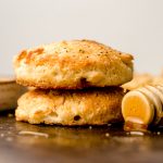 a stack of buttermilk biscuits with a honey dipper