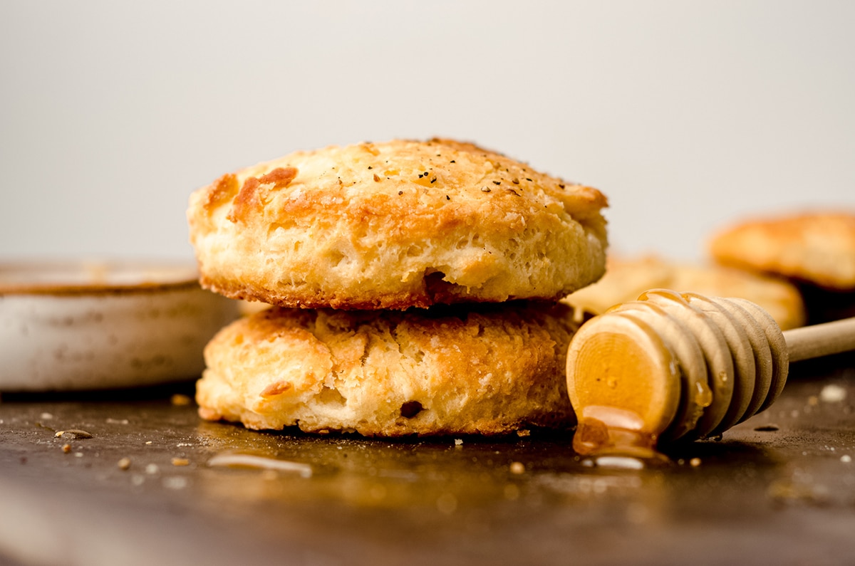 a stack of buttermilk biscuits with a honey dipper