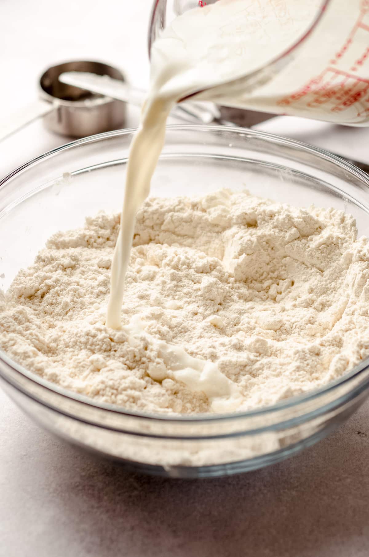 adding buttermilk to dry ingredients for buttermilk biscuits in a bowl