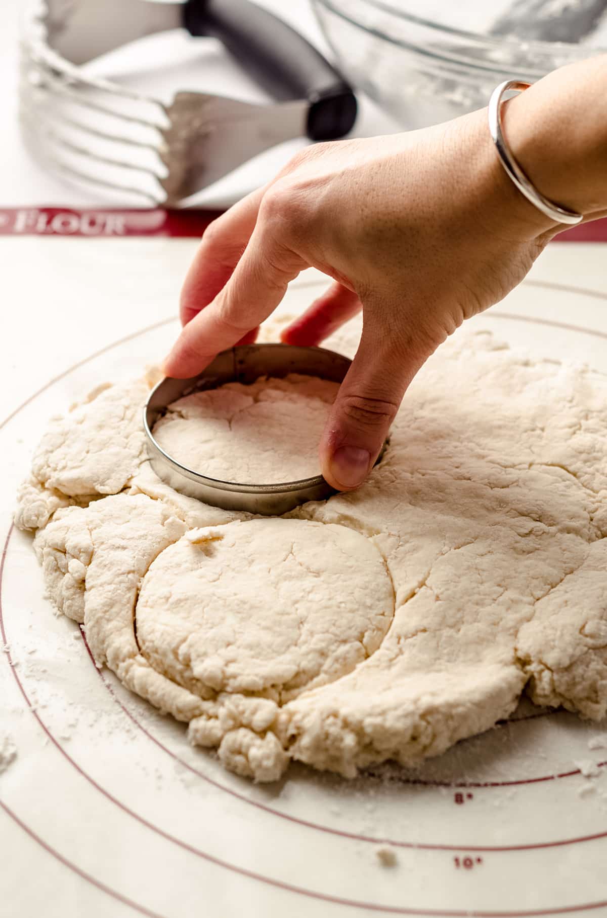 using a round cutter to cut biscuit dough