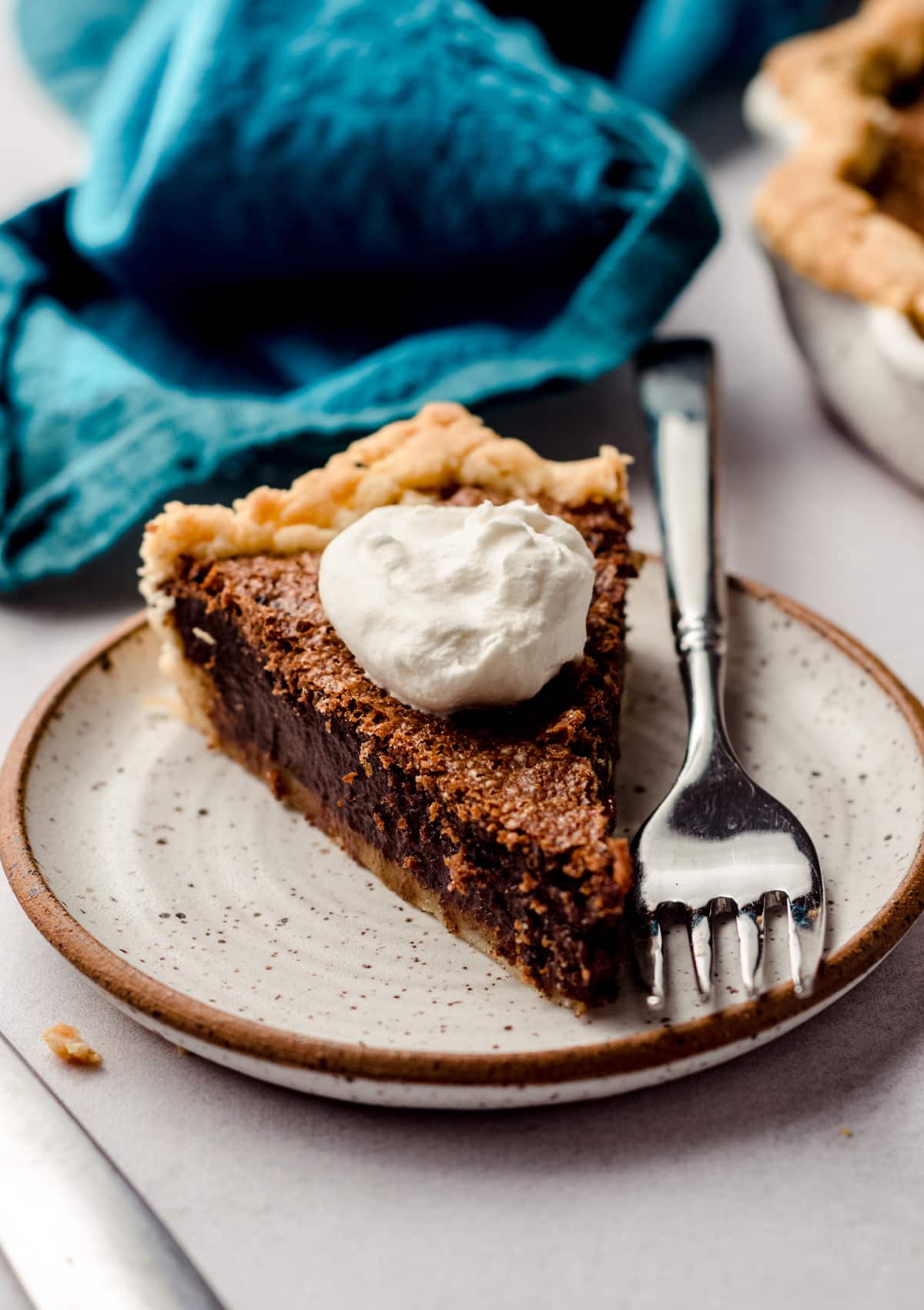 slice of chocolate chess pie with whipped cream and a fork on a plate