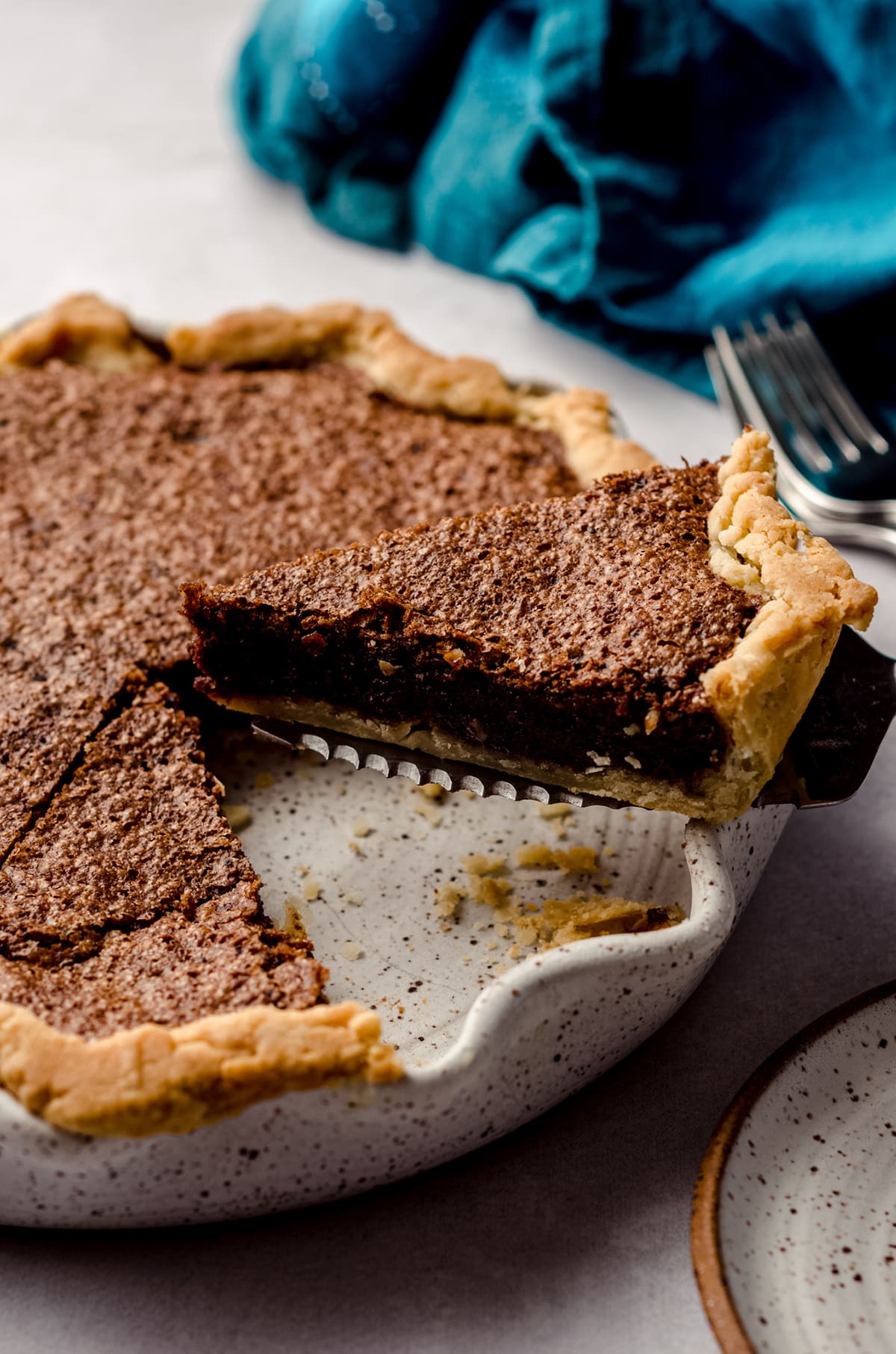 slice of chocolate chess pie being lifted out of a pie plate with a pie server