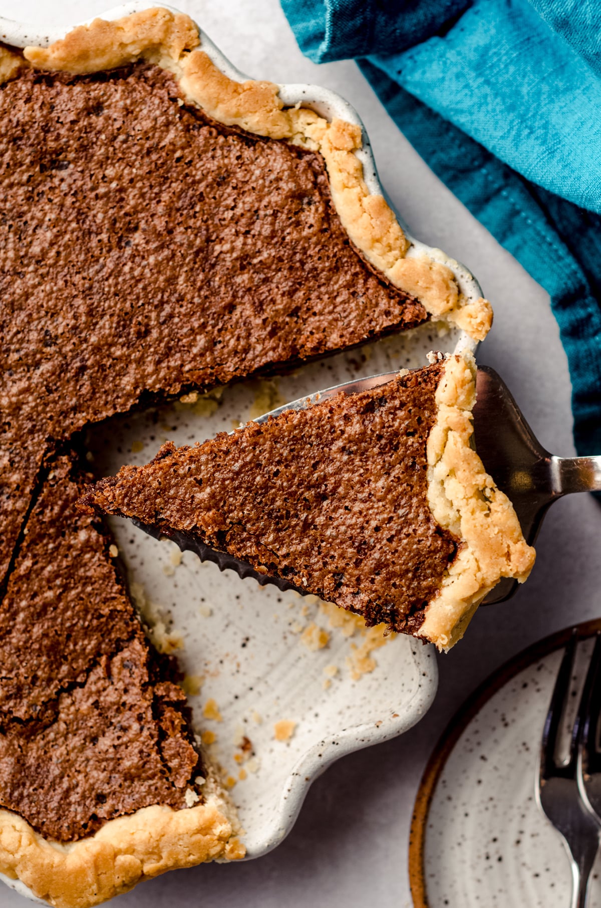 aerial photo of a slice of chocolate chess pie being lifted out of a pie plate with a pie server