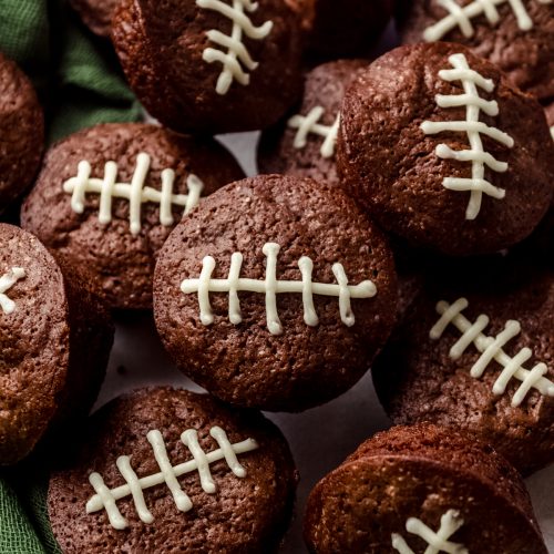 Football brownie bites on a surface with a green kitchen textile around them.