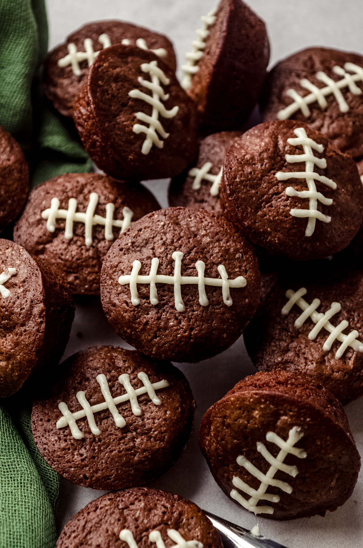 Football brownie bites on a surface with a green kitchen textile around them.