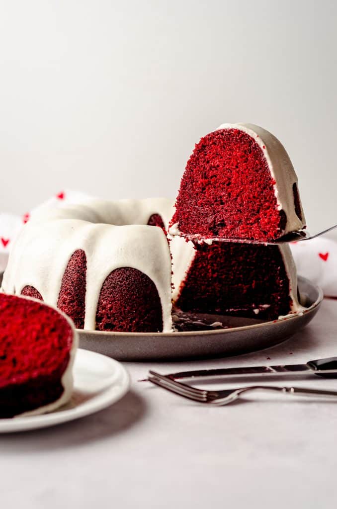 lifting a slice of red velvet bundt cake with a cake server