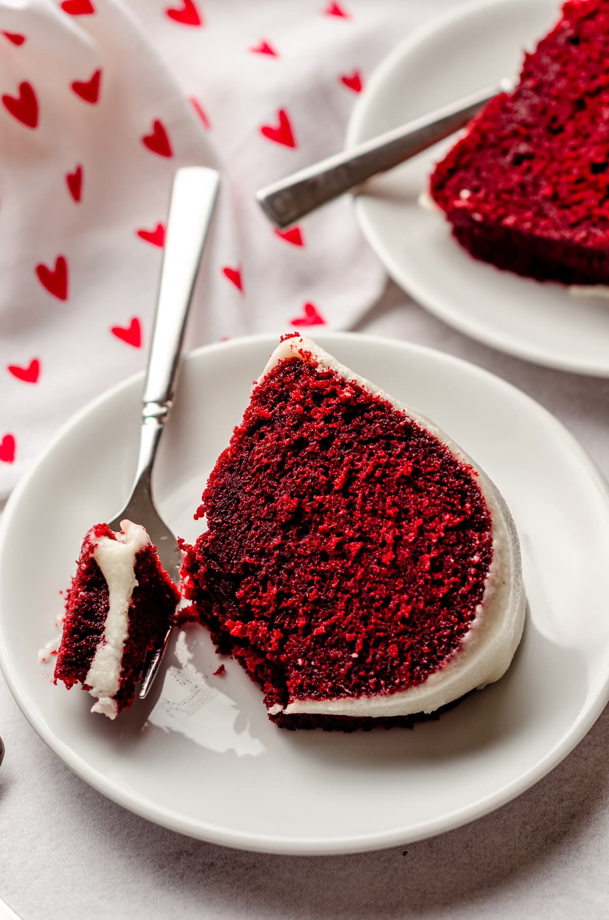 slice of red velvet bundt cake on a plate with a bite taken out of it