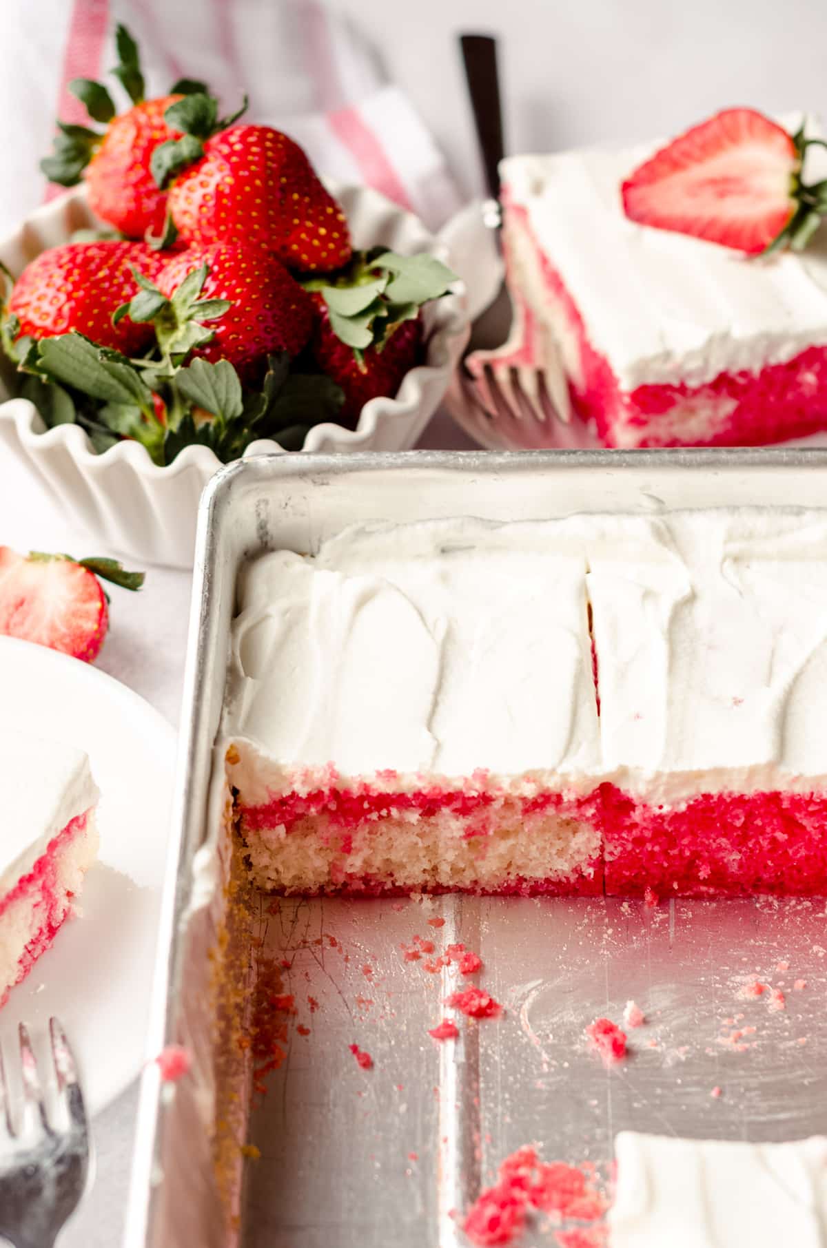 strawberry poke cake sliced in a sheet pan