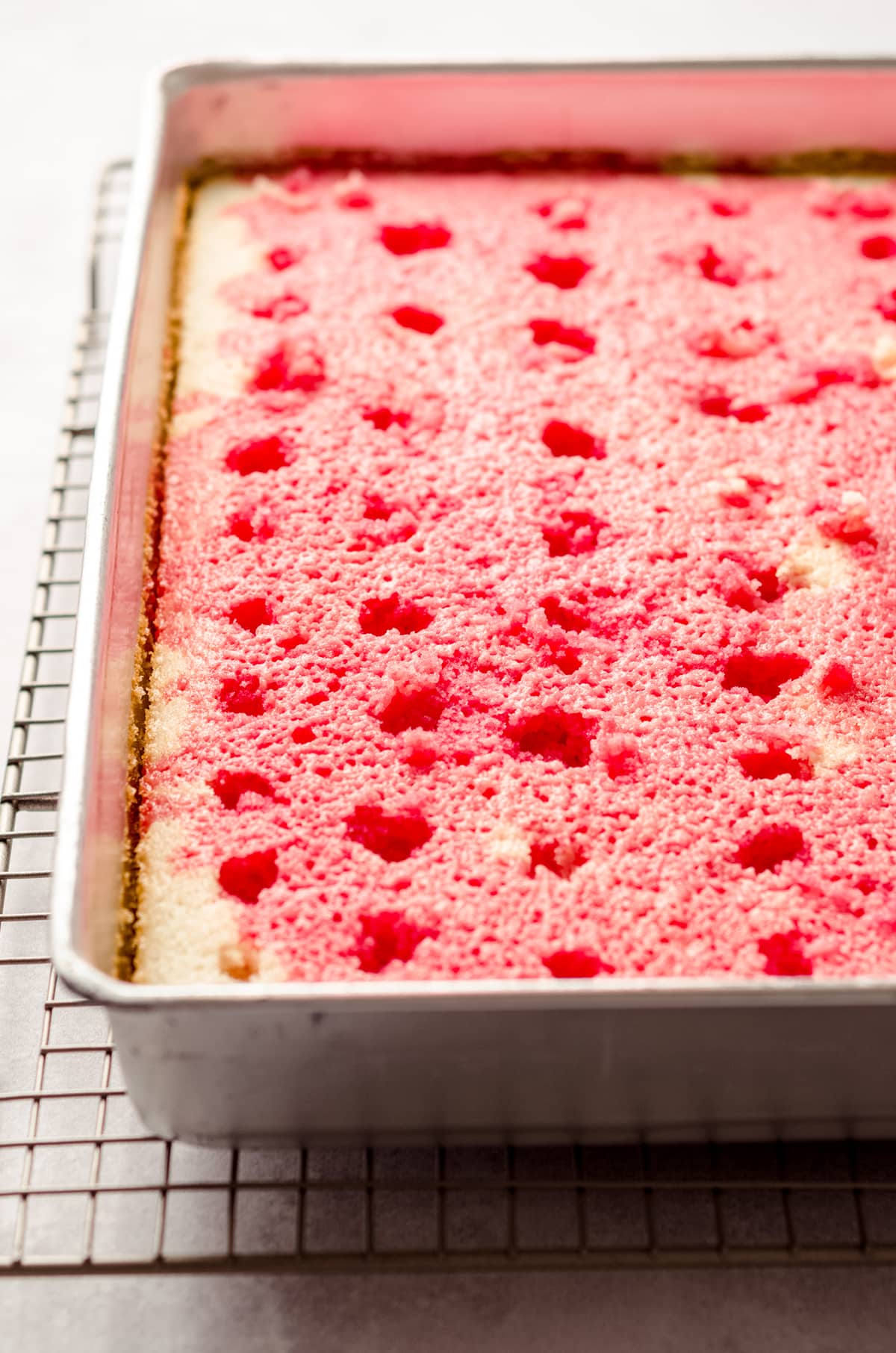 strawberry poke cake with jello poured over it