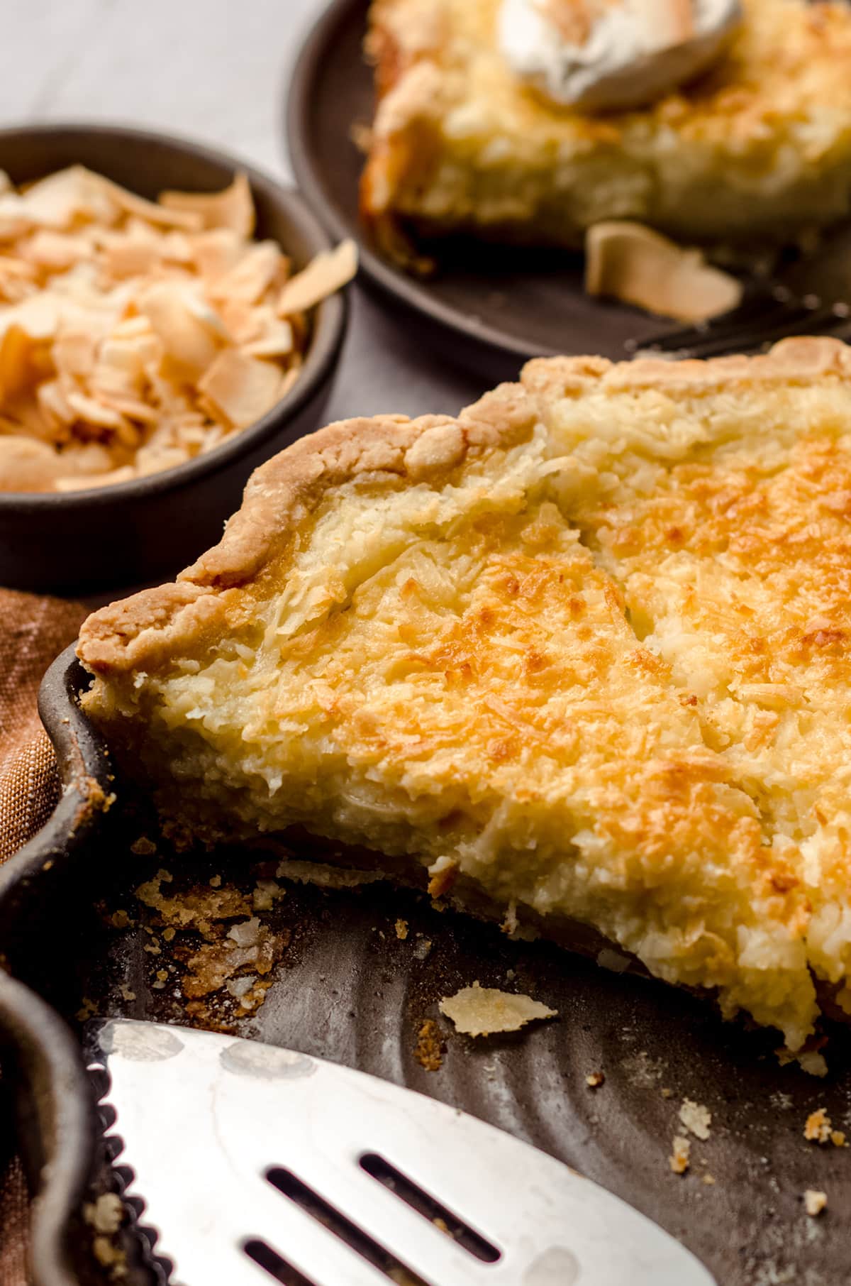 Several slices of pie inside of a pie dish, with a serving utensil in the foreground.