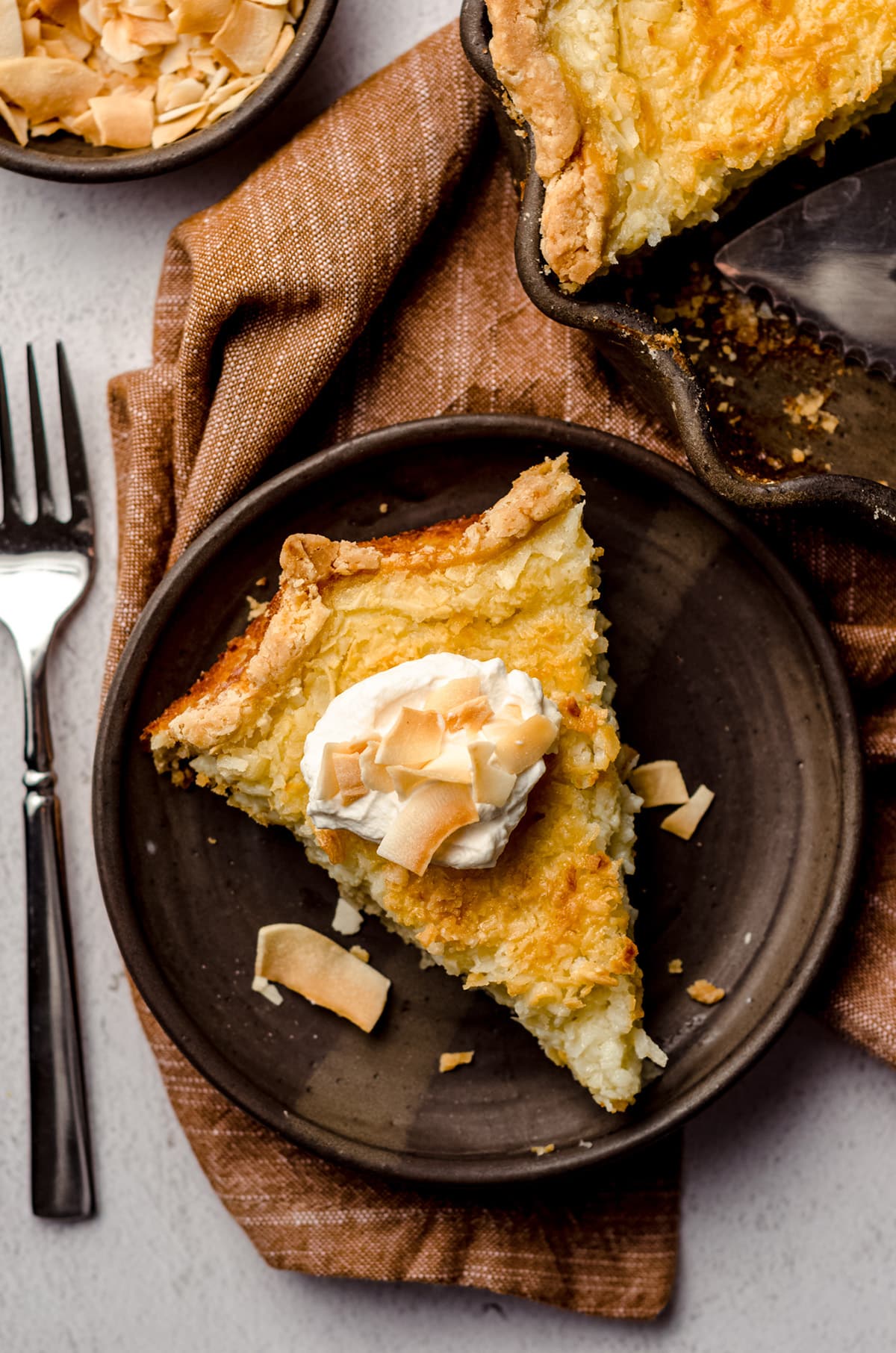 An overhead shot of a piece of pie, topped with a dollop of whipped cream.