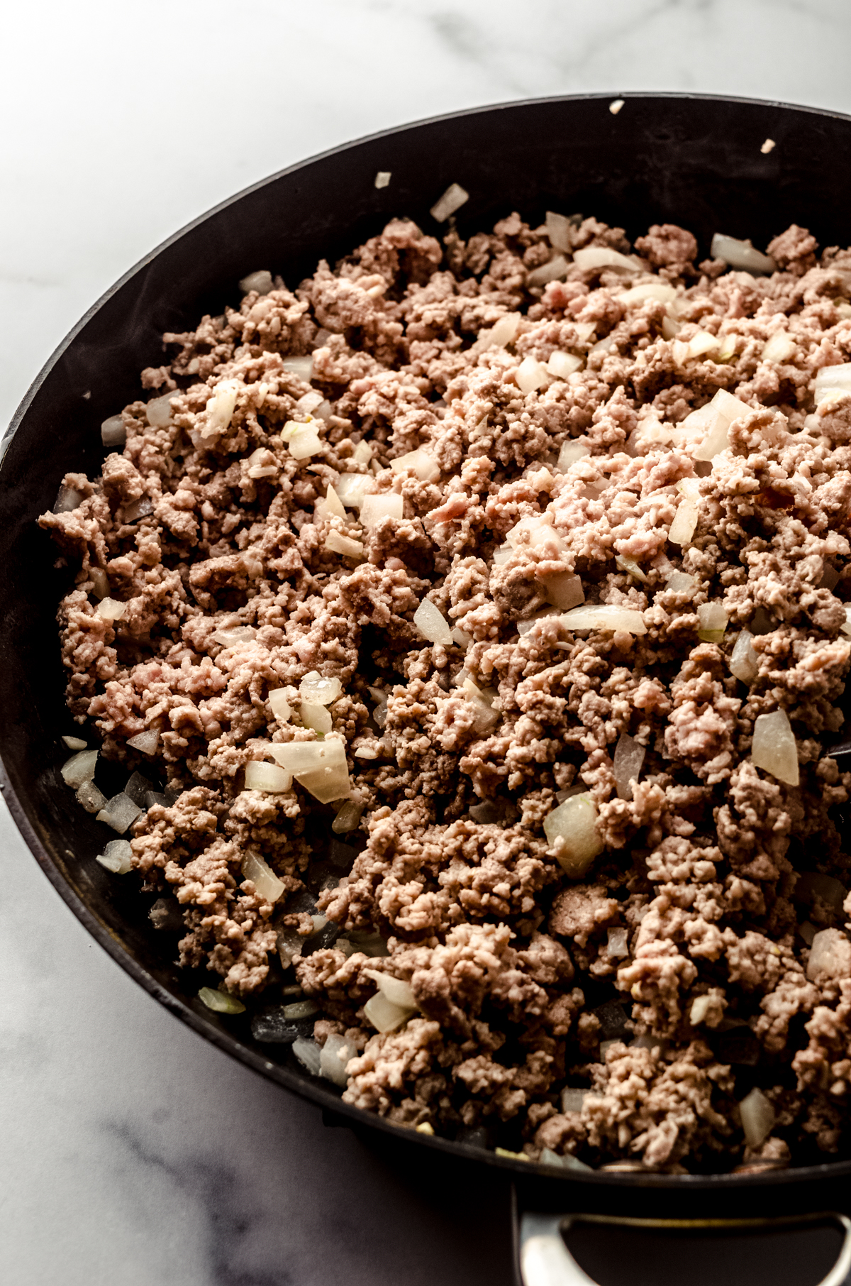 The meat and onion mixture base for meat sauce in a saucepan.