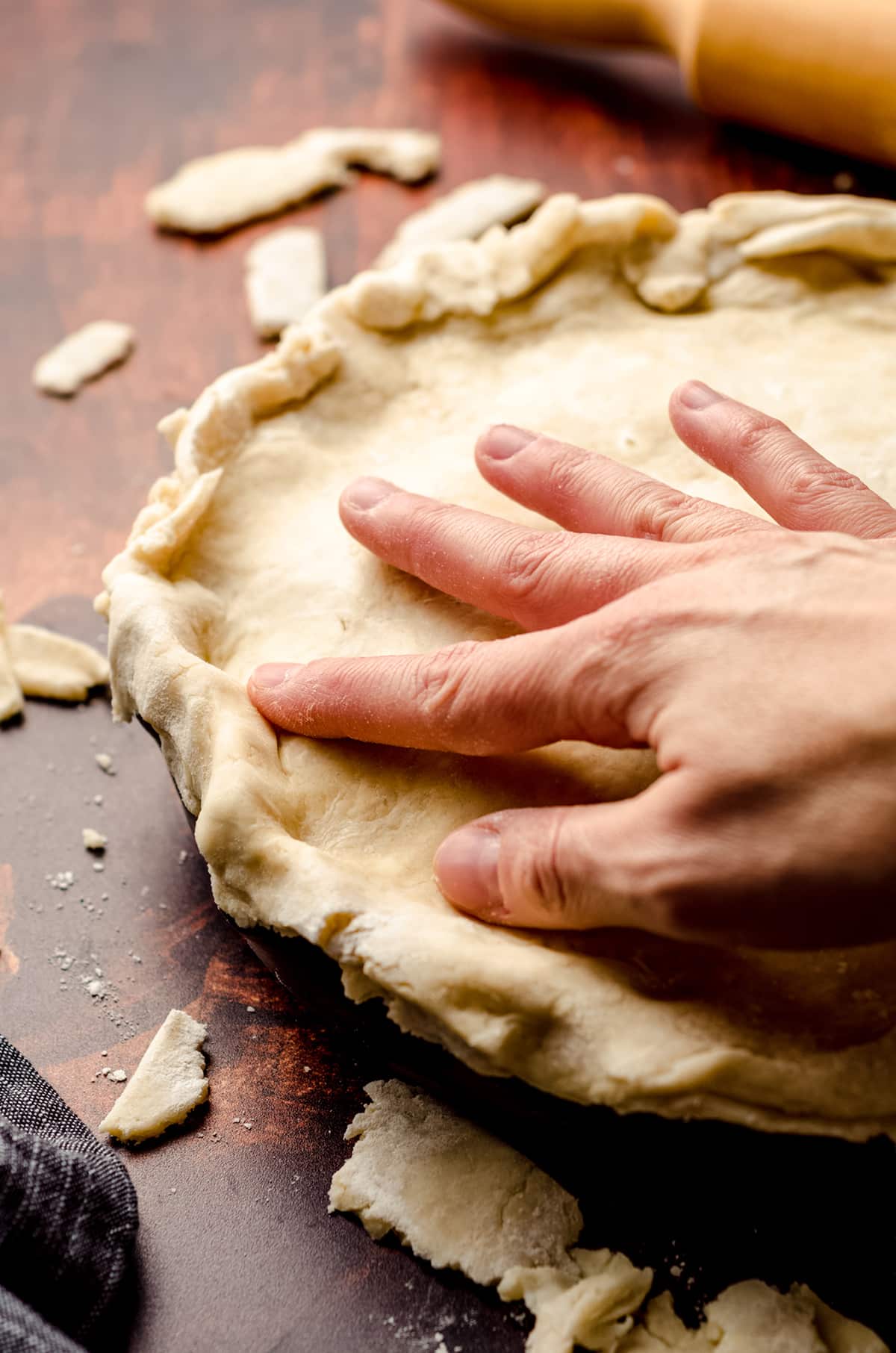 hand pressing a pie crust onto chicken pot pie