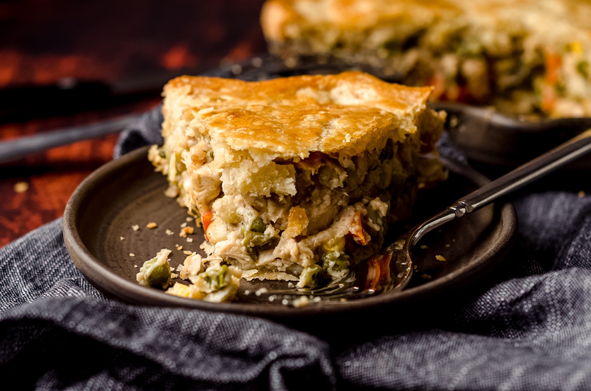 double crust chicken pot pie slice on a plate with a bite taken out of it