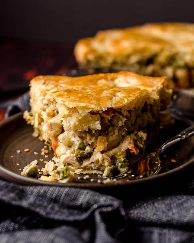 double crust chicken pot pie slice on a plate with a bite taken out of it