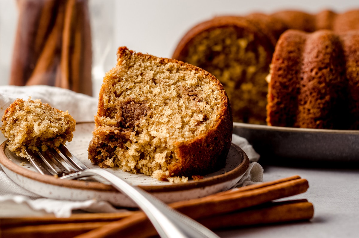 slice of cinnamon streusel coffee cake on a plate with a fork and a bite taken out of it