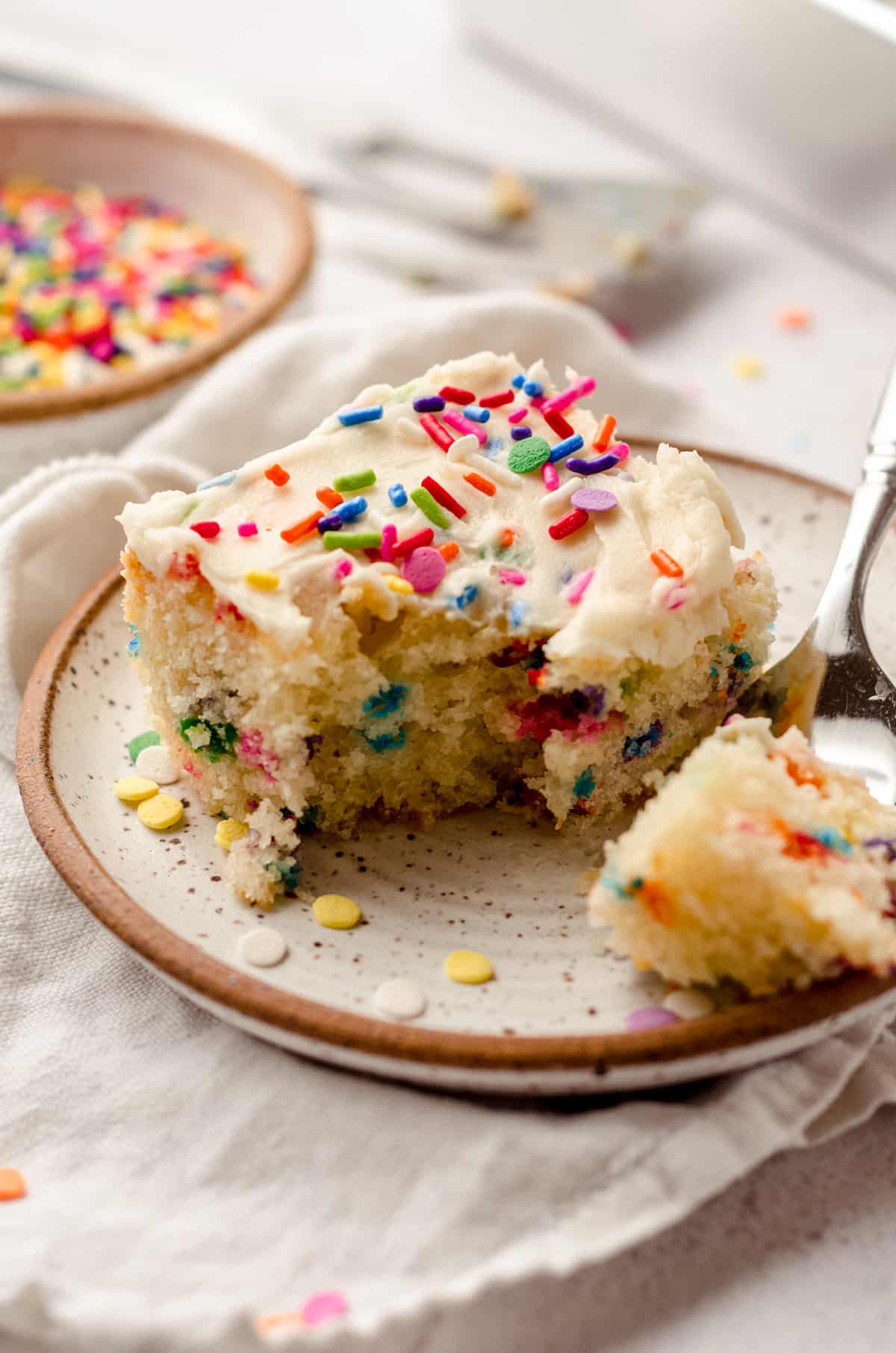 A square of funfetti sheet cake, with the fork taken out.