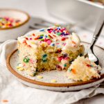 A piece of sheet cake with sprinkles, with a fork having taken a piece out.