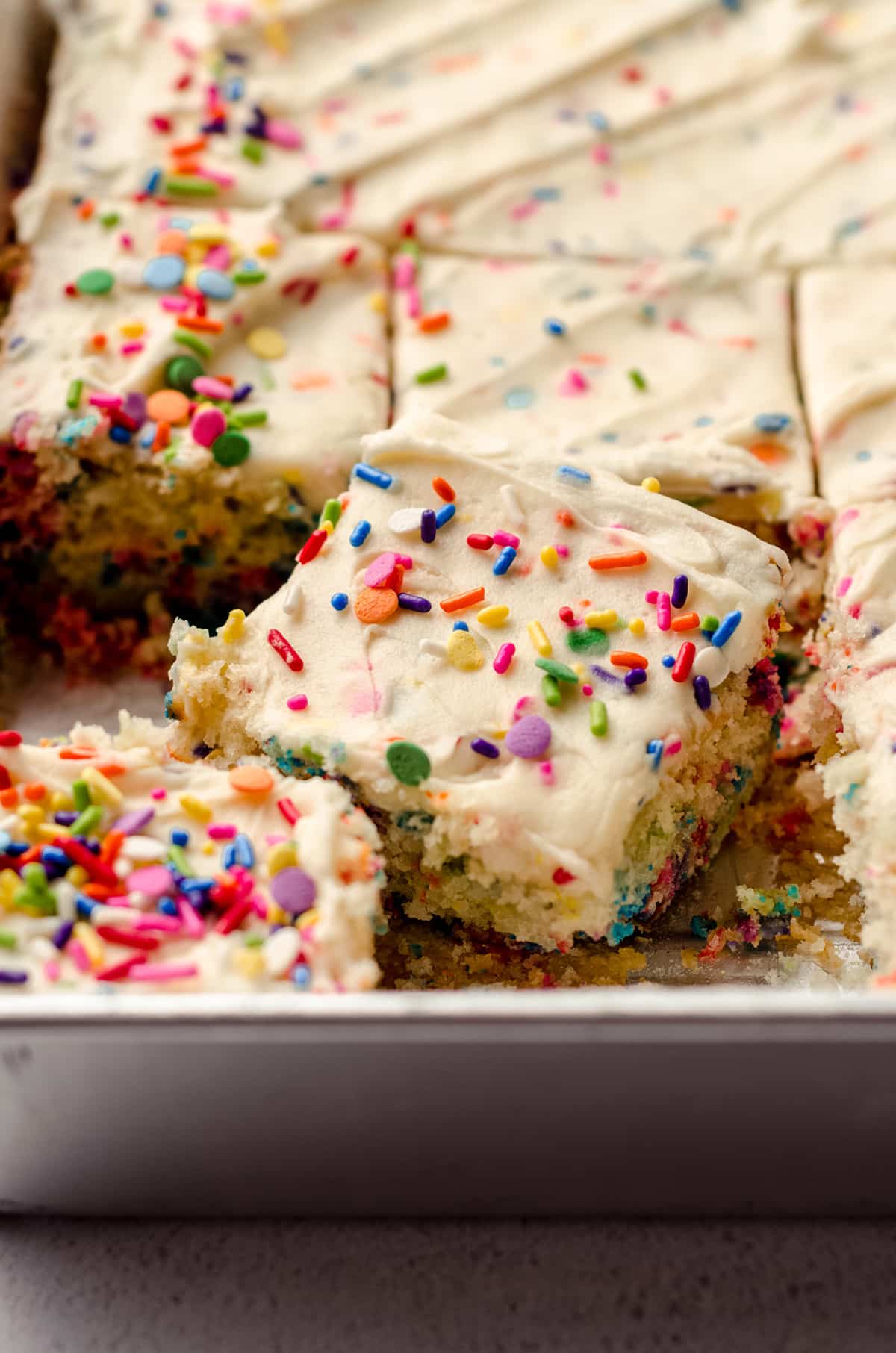 A baking pan filled with sheet cake, topped with sprinkles.