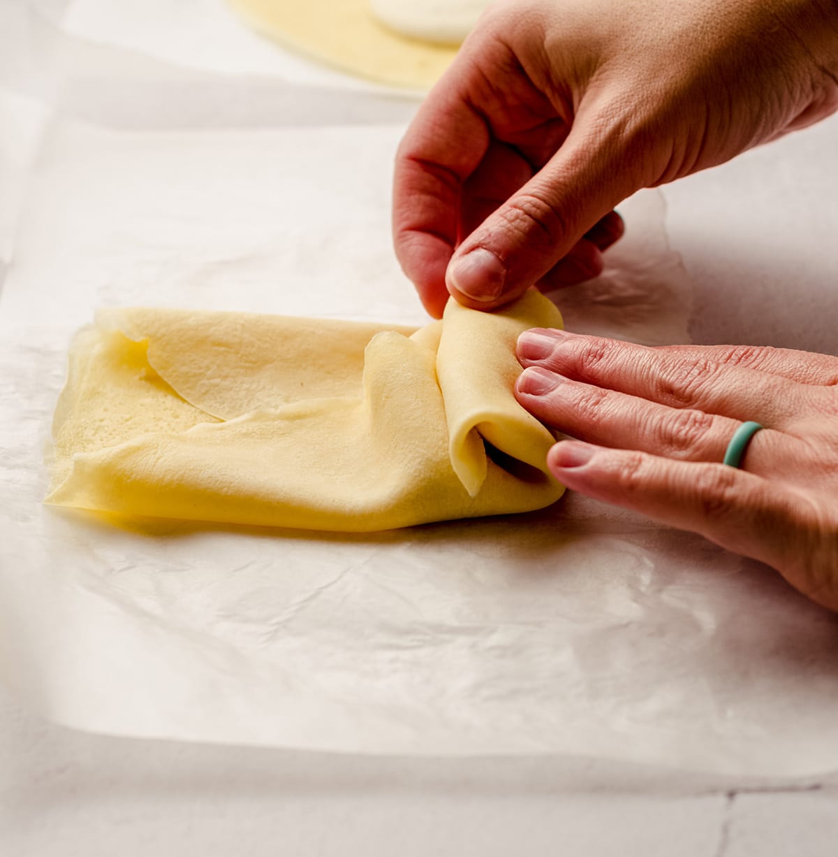 Rolling cheese blintzes by hand.