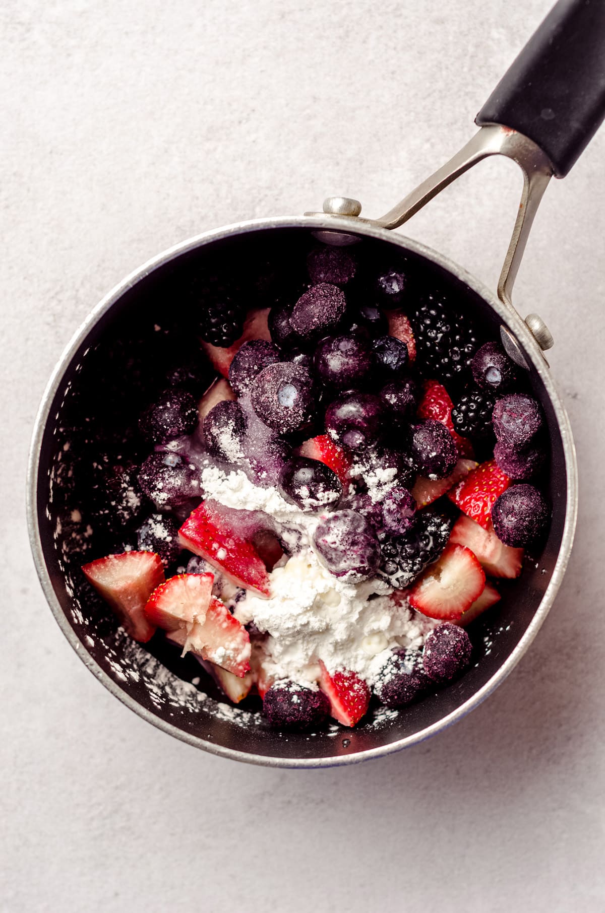 Adding lemon juice, sugar, and cornstarch added to a small saucepan along with berries.
