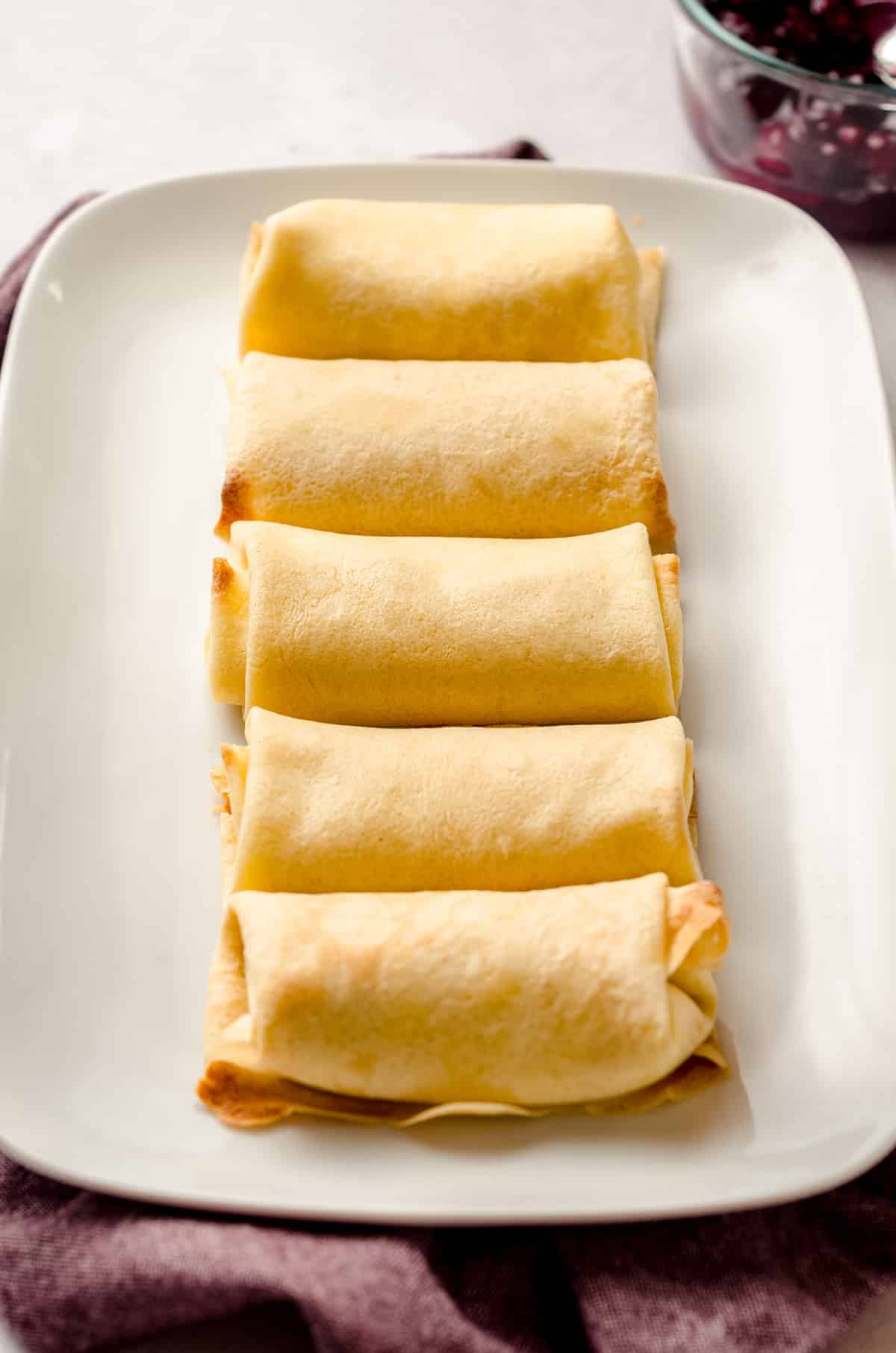Baked cheese blintzes lined up on a platter.