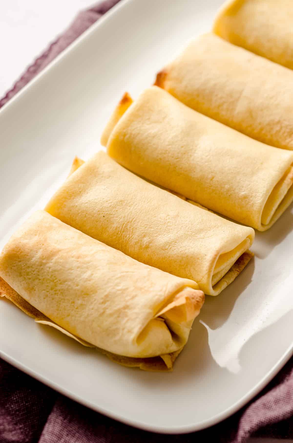 Rolled and baked cheese blintzes on a large white platter.