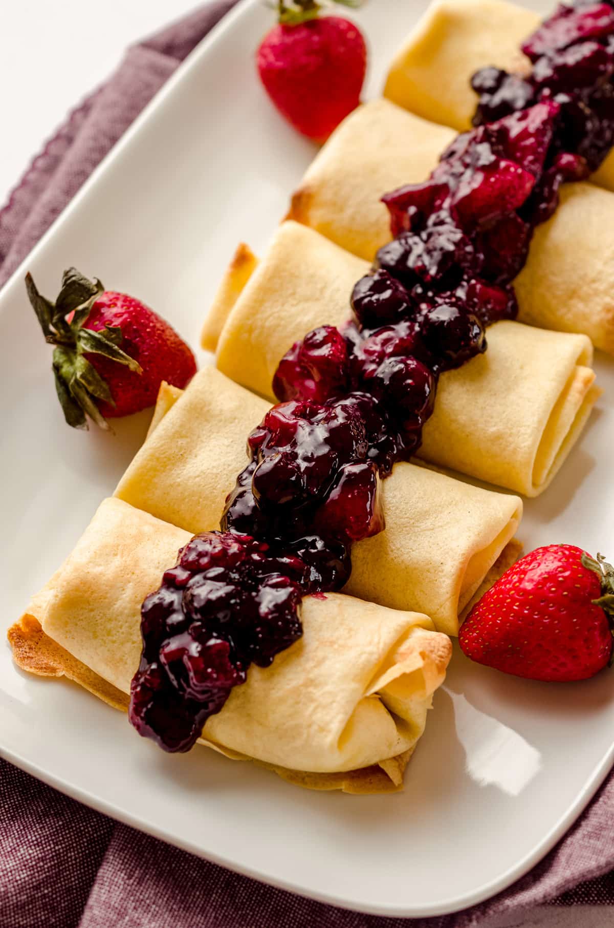 A platter of cheese blintzes and topped with berry compote.