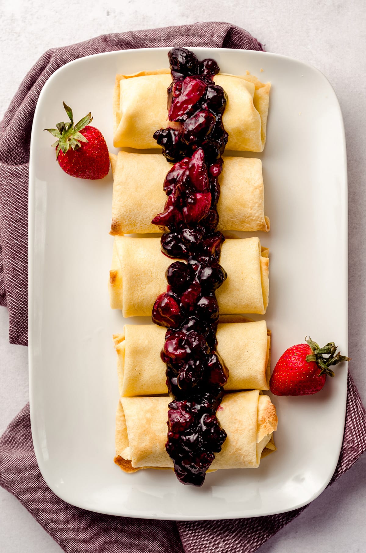 Rolled cheese blintzes topped with a berry compote.