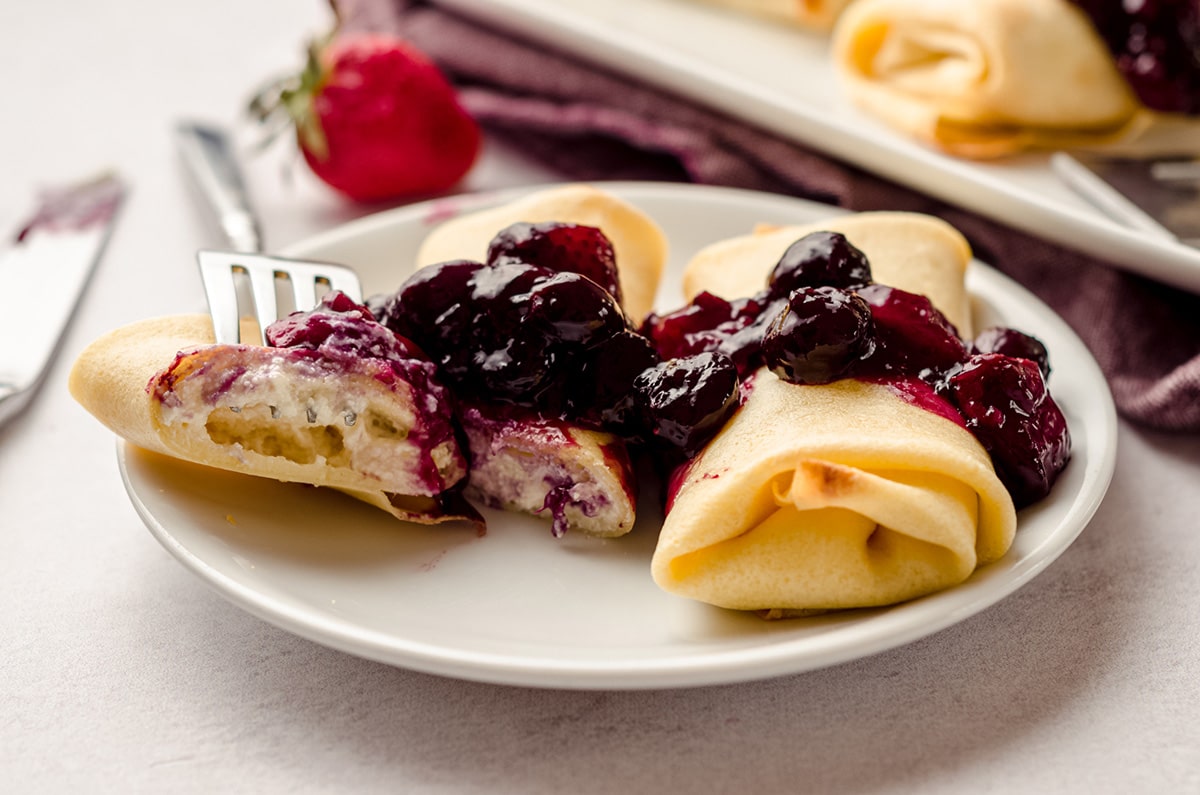 Two rolled cheese blintzes, topped with berry compote.