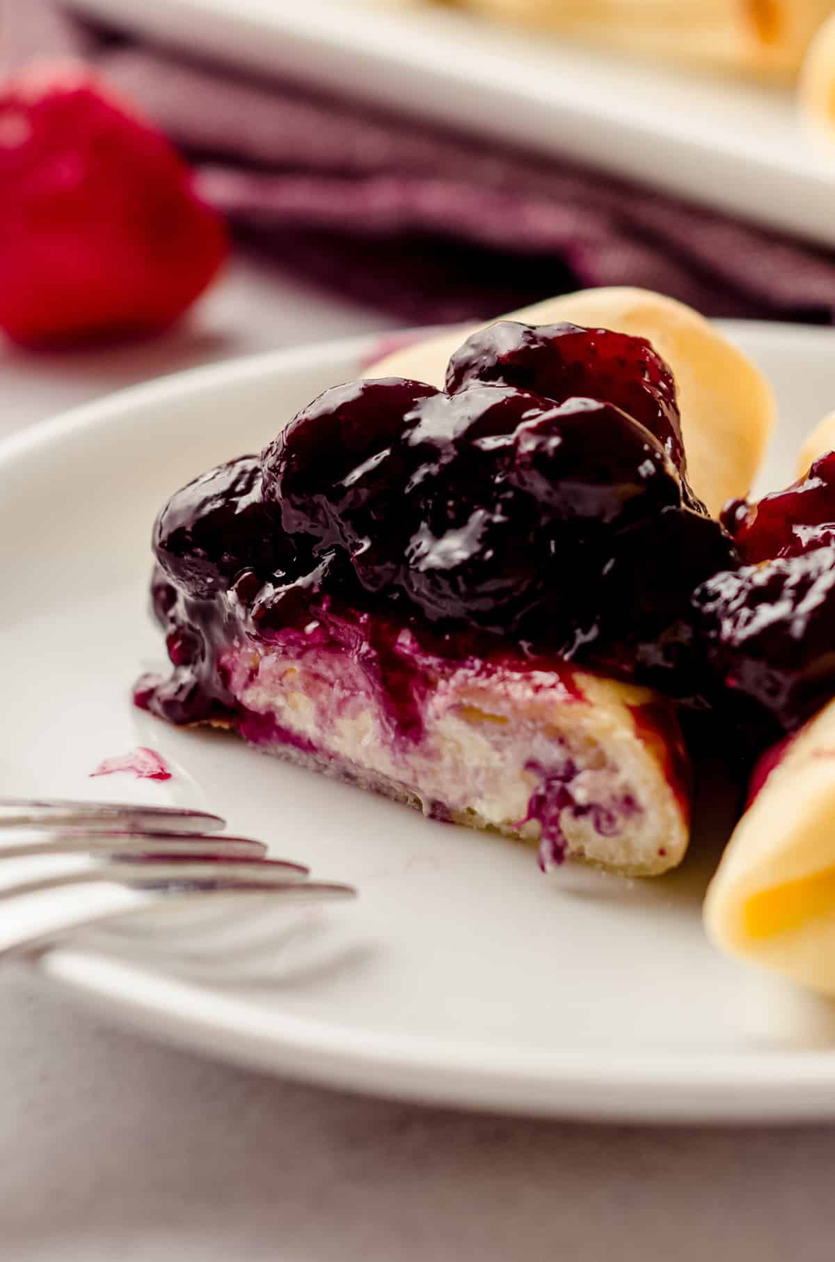 A rolled cheese blintz, cut and topped with berry compote.