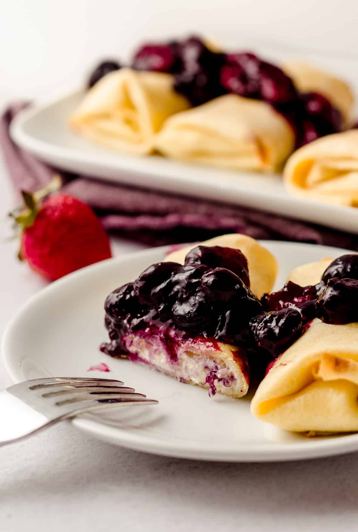 Rolled cheese blintzes that have been cut into it, topped with a berry compote.