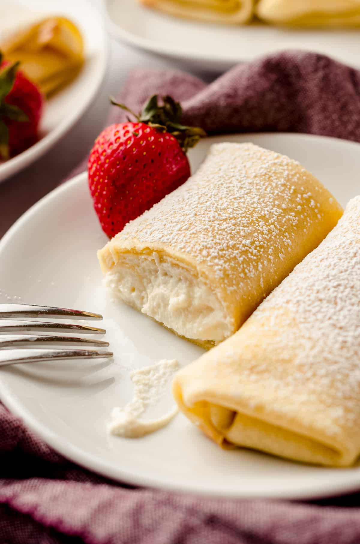 A close up of a rolled crepe with ricotta filling.