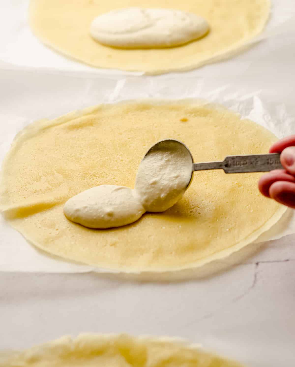 Spooning cheese blintz filling onto a crepe.