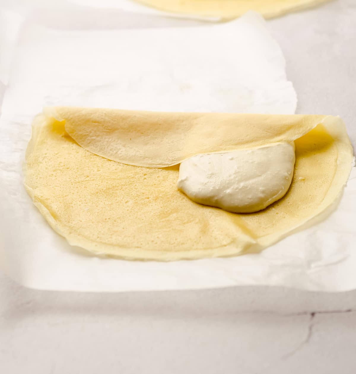 Folding the sides of the crepe over the cheese blintz filling.