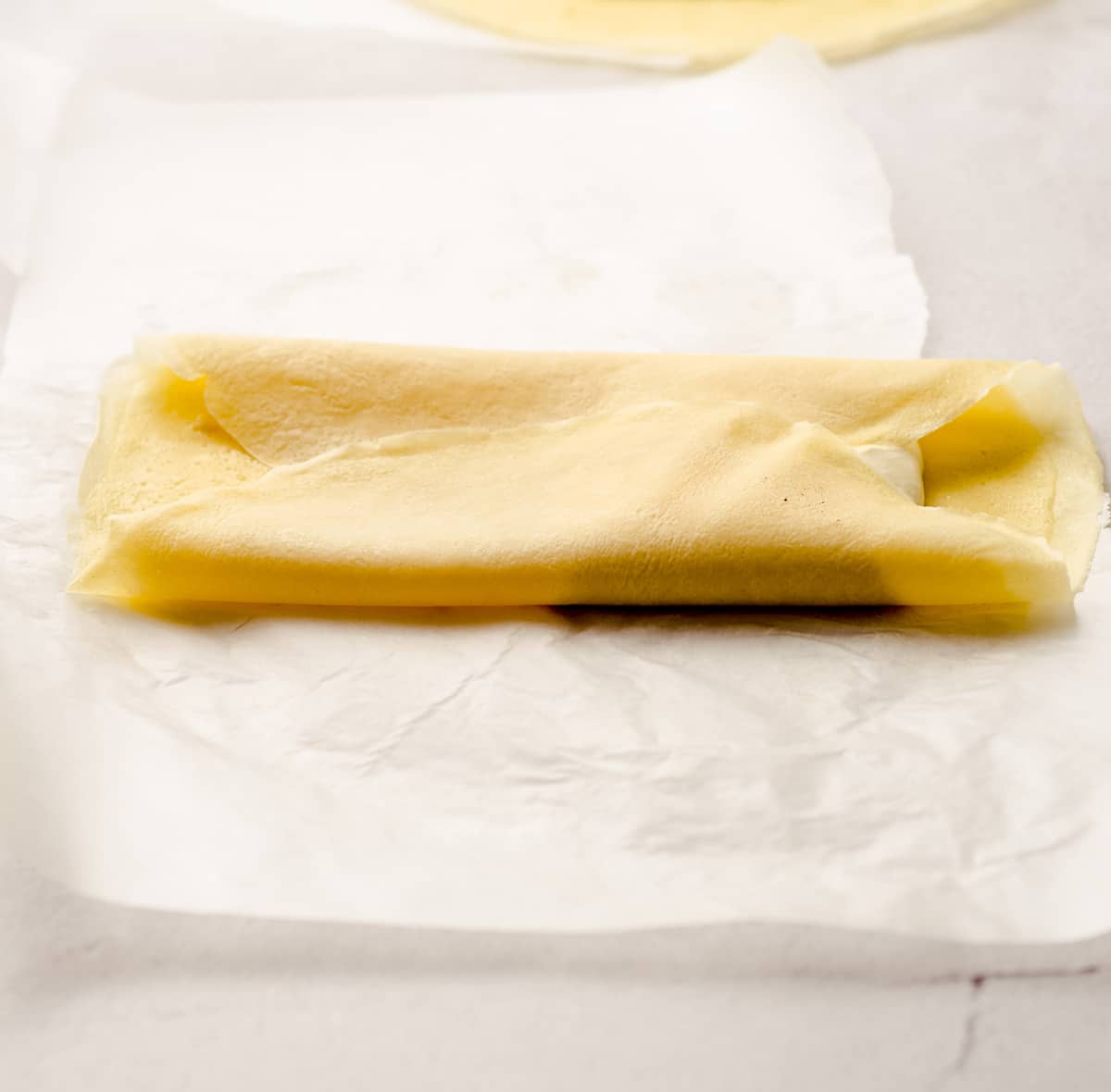 Folding the sides of a crepe over a cheese filling.
